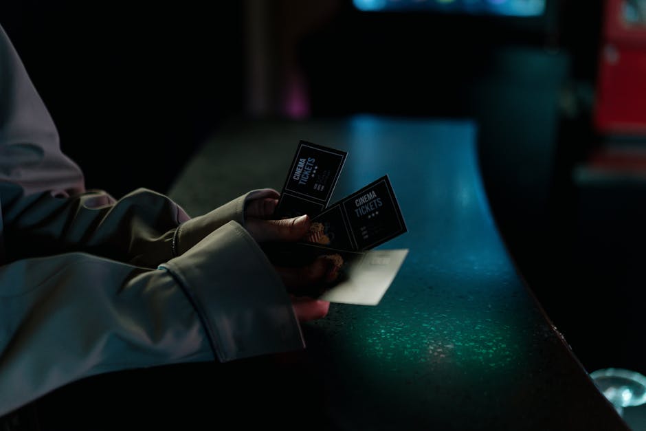 Moody image of a person holding cinema tickets at night, highlighting anticipation of a movie night.